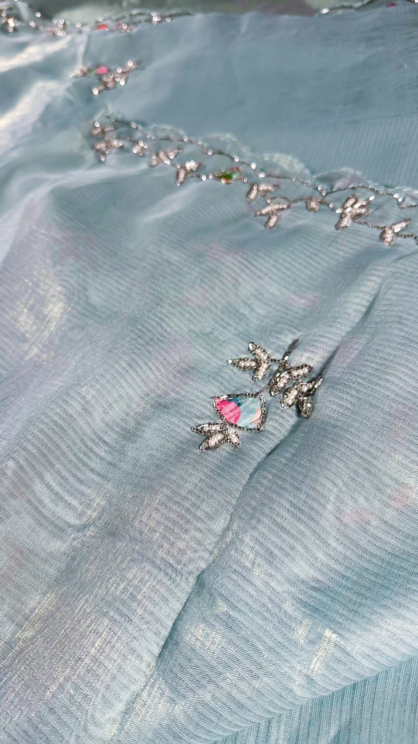 Detailed view of saree border embroidery with crystal embellishments and traditional vine patterns on silk fabric