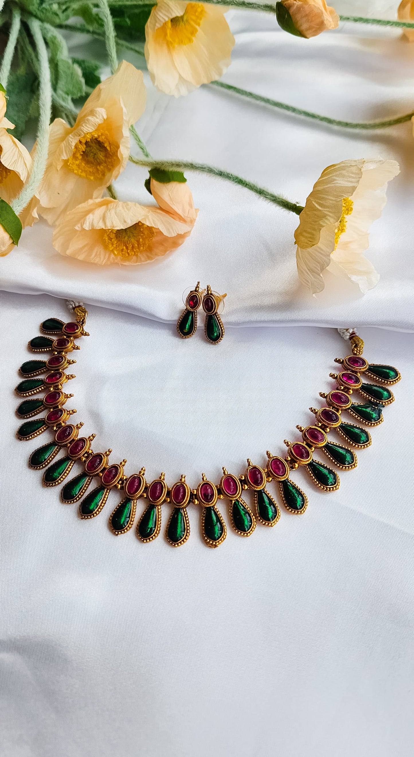 South Indian antique ruby-green heritage necklace set with matching earrings on white silk background
