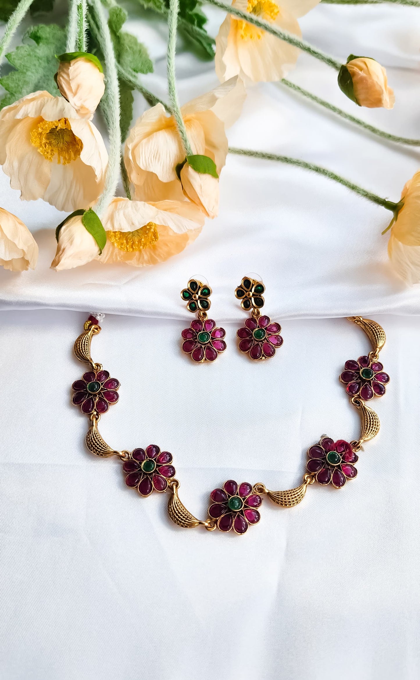 Traditional gold-plated necklace with ruby and green kundan stones, styled with matching earrings.