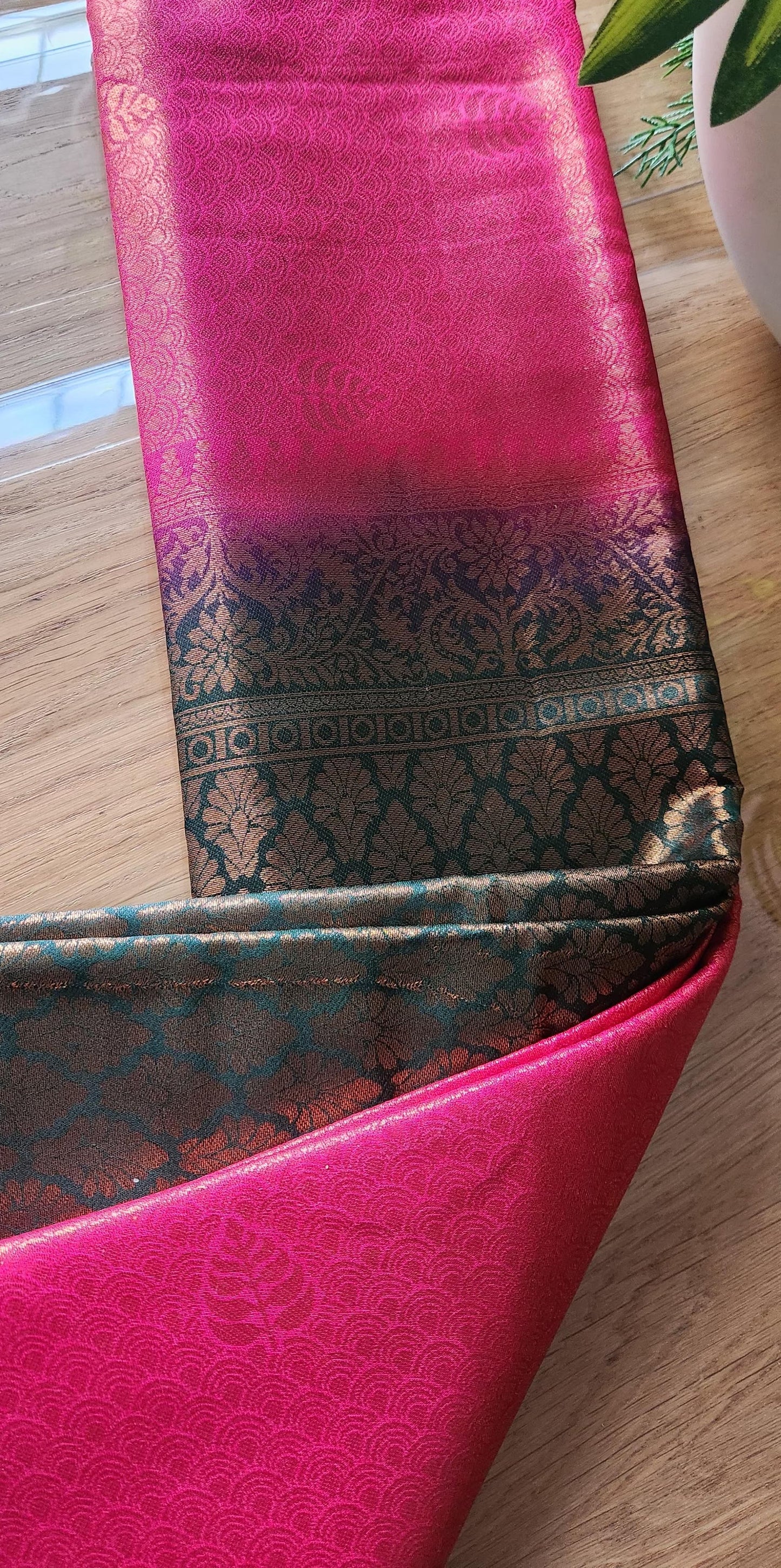 Kubera silk saree with a double-shaded woven silk body and intricately detailed traditional border, neatly styled on a wooden surface with minimal décor.