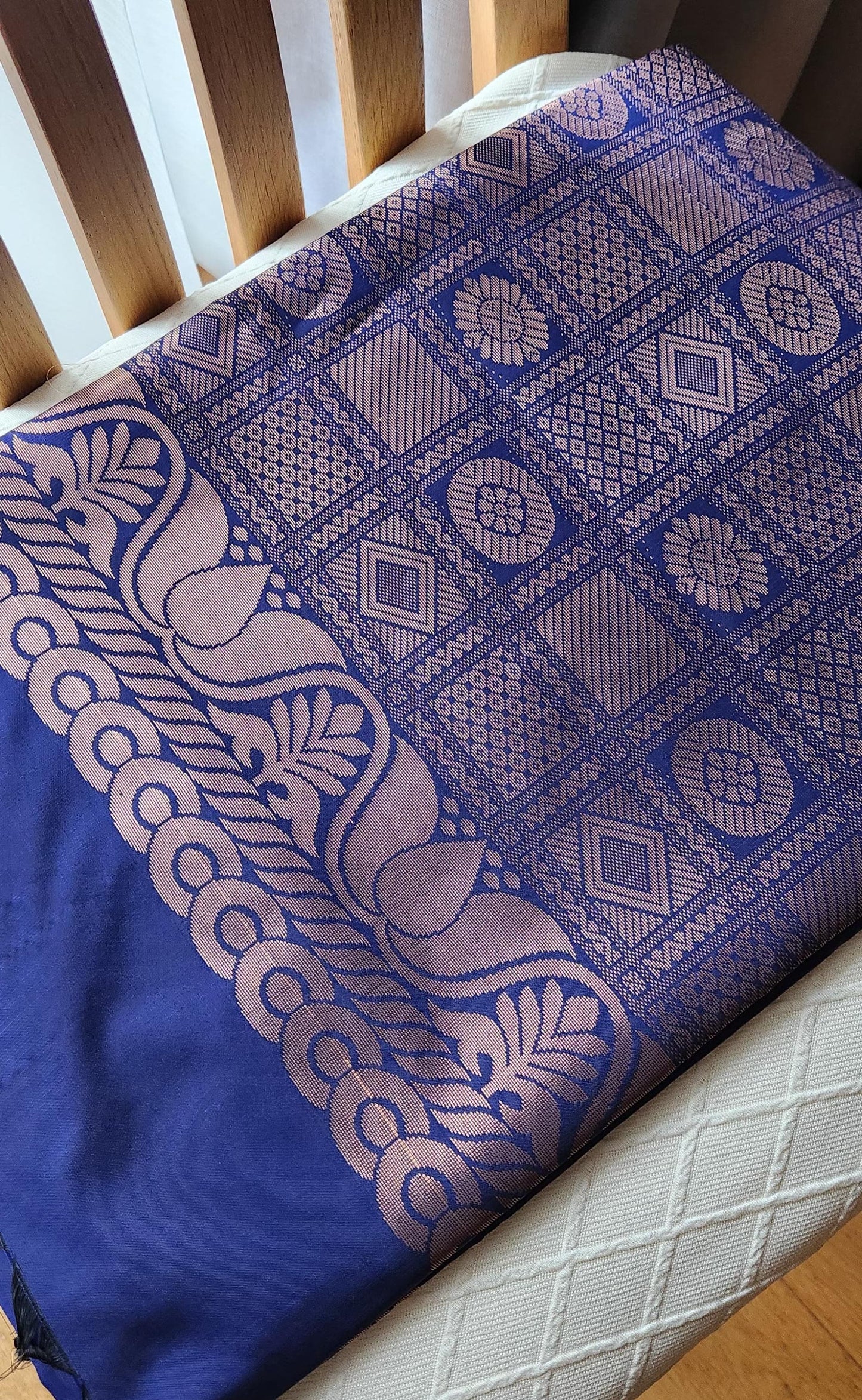 Deep navy blue silk saree with antique gold zari floral buttas and black tassels laid flat