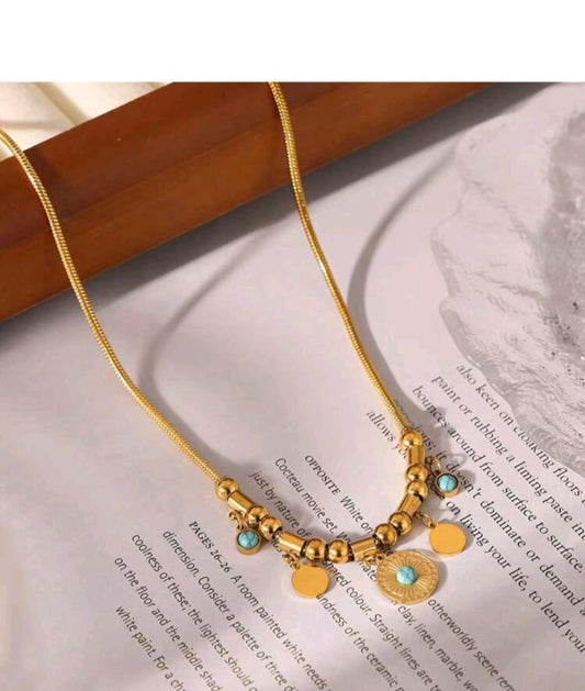 Bohemian gold statement necklace with turquoise stone accents, textured medallion and mixed coin charms on snake chain - artisanal designer jewellery UK