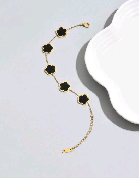 Sophisticated gold chain bracelet with five black onyx clover motifs - elegant designer jewellery featuring genuine black stones for UK customers