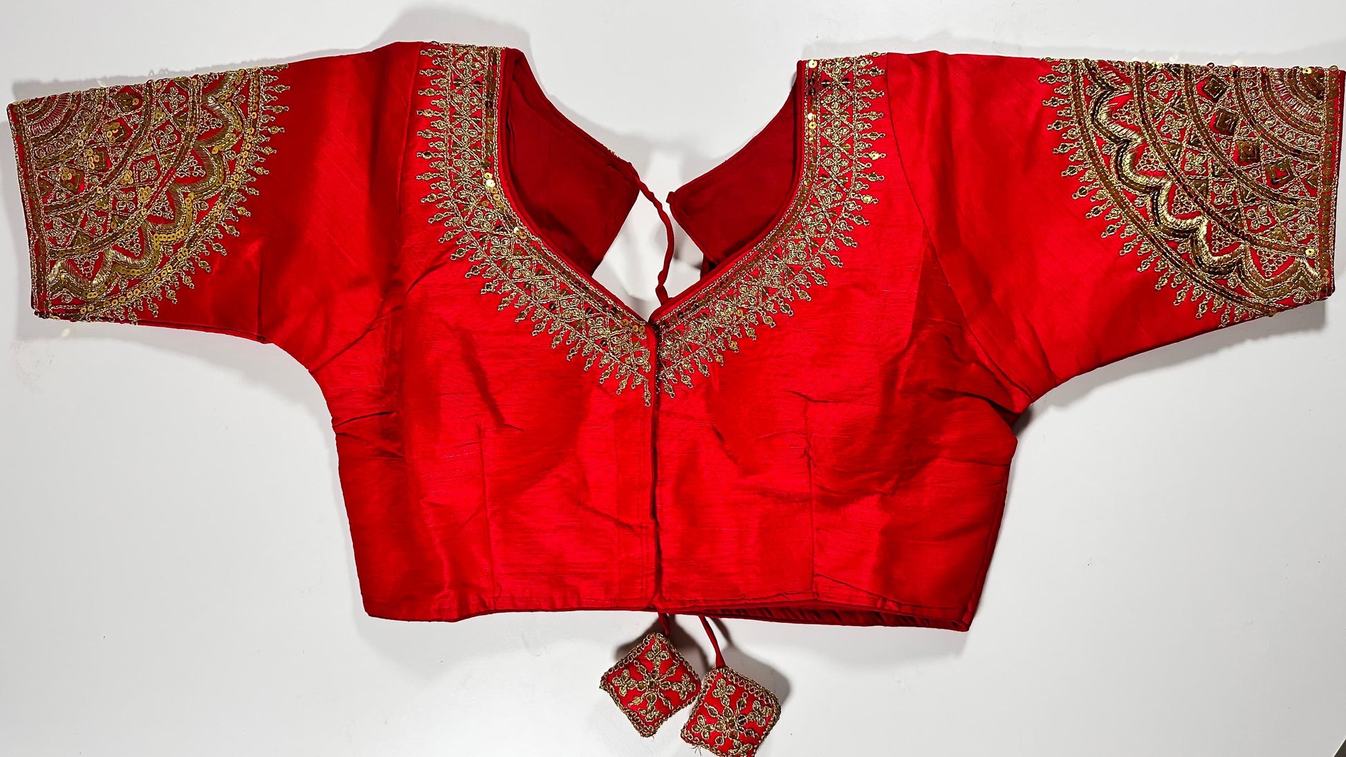 Red embroidered saree blouse with heavy zardozi work showing traditional Indian bridal choli design with intricate gold handwork