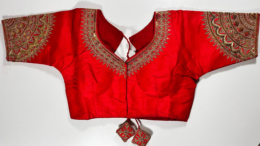 Red embroidered saree blouse with heavy zardozi work showing traditional Indian bridal choli design with intricate gold handwork