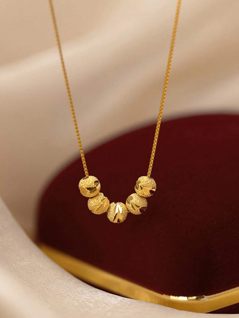 Elegant gold necklace with five textured ball beads in graduated sizes on delicate chain - contemporary designer jewellery for UK customers