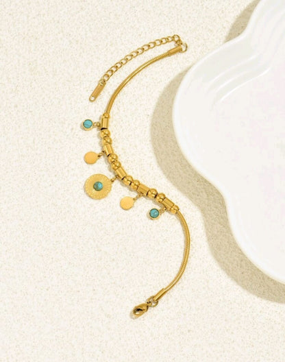Bohemian gold charm bracelet with turquoise stone accents, textured disc and coin charms on beaded chain - artisanal designer jewellery for UK boho styling