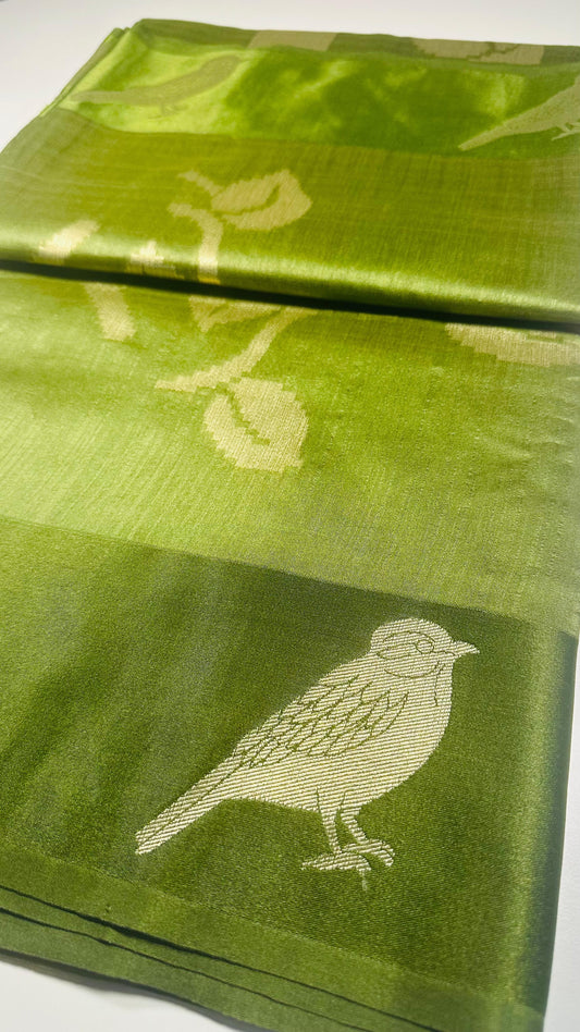 Green silk saree with woven bird and leaf motifs showing nature-inspired traditional Indian design and lustrous silk fabric