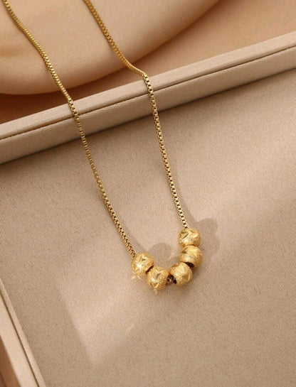 Elegant gold necklace with five textured ball beads in graduated sizes on delicate chain - contemporary designer jewellery for UK customers