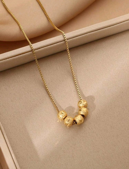 Elegant gold necklace with five textured ball beads in graduated sizes on delicate chain - contemporary designer jewellery for UK customers