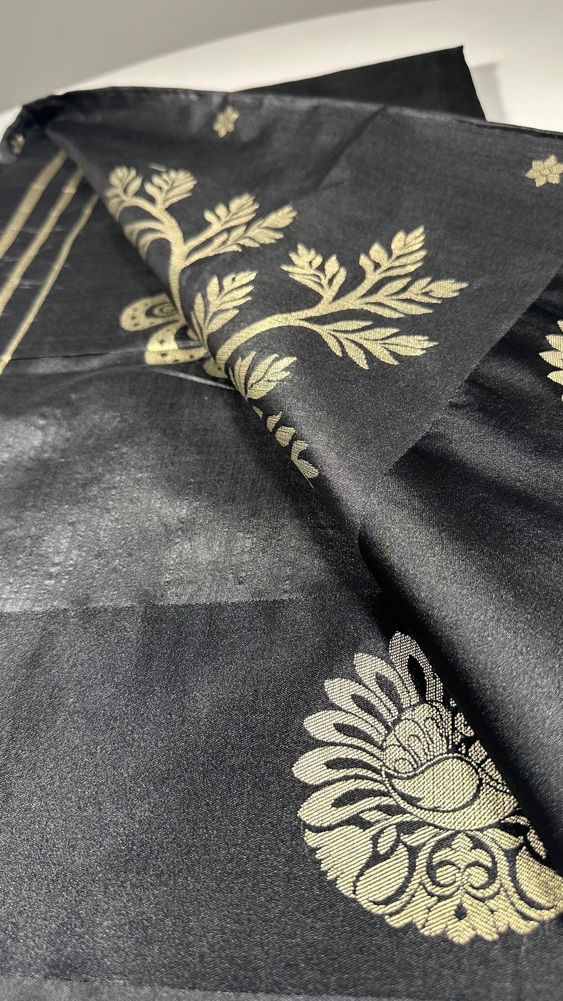 Black silk saree with gold woven floral motifs showing elegant traditional Indian design and luxurious silk fabric texture