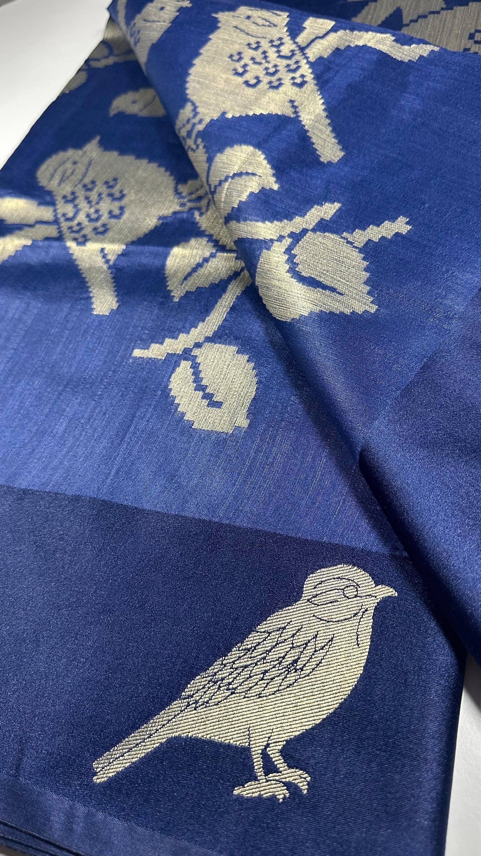 Royal blue silk saree with woven bird and floral motifs showing nature-inspired traditional Indian design and lustrous silk fabric quality
