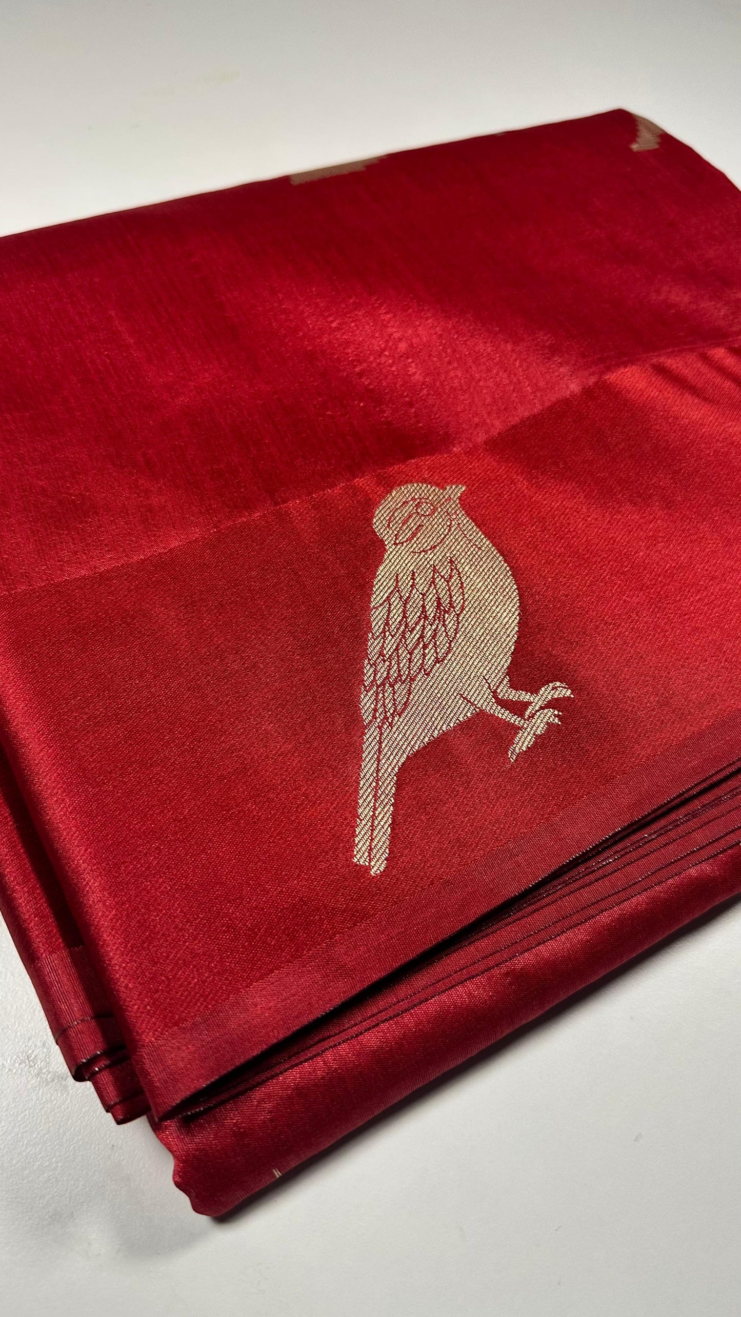  Red silk saree with woven bird and floral motifs showing traditional Indian wedding design and lustrous silk fabric with gold zari work