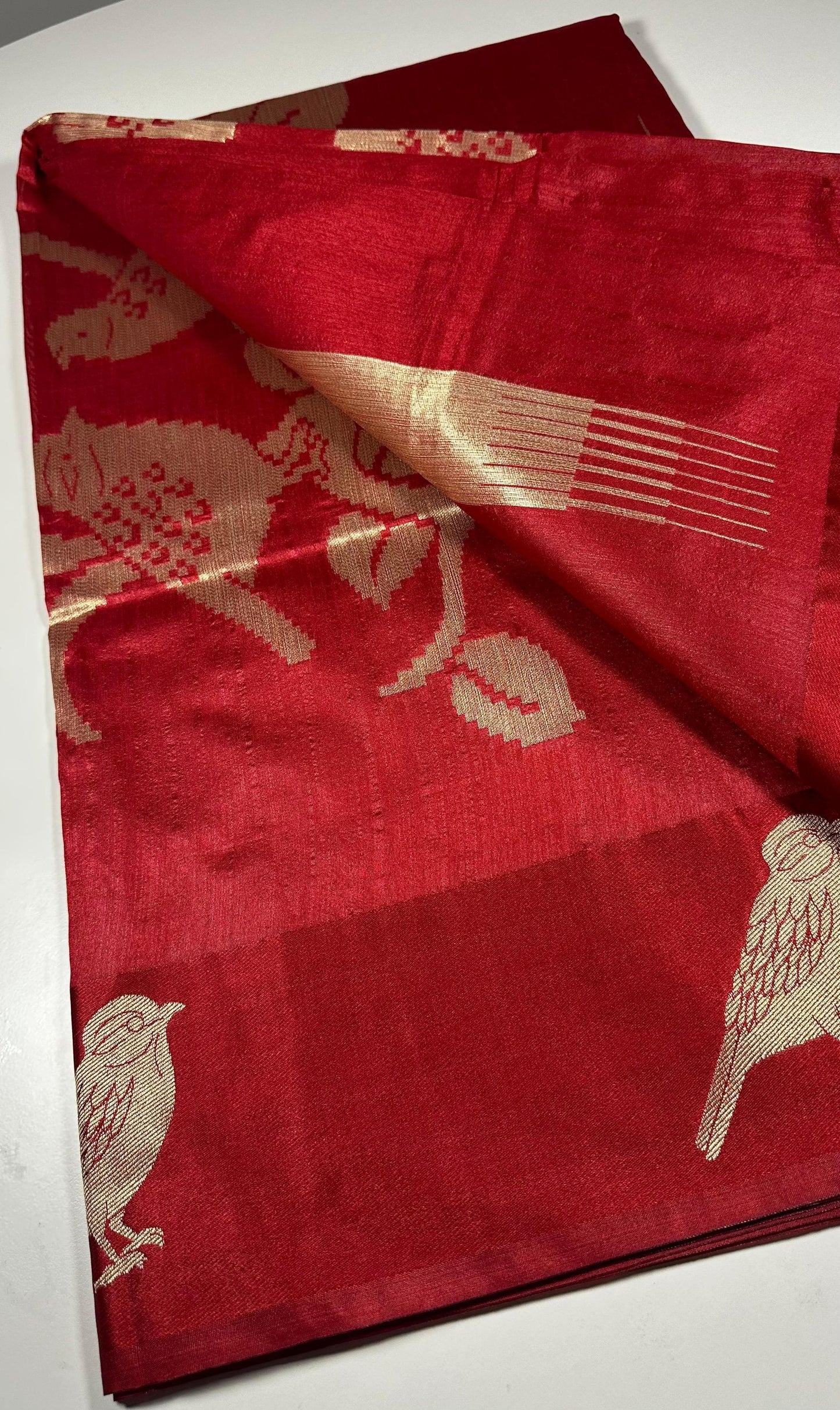  Red silk saree with woven bird and floral motifs showing traditional Indian wedding design and lustrous silk fabric with gold zari work
