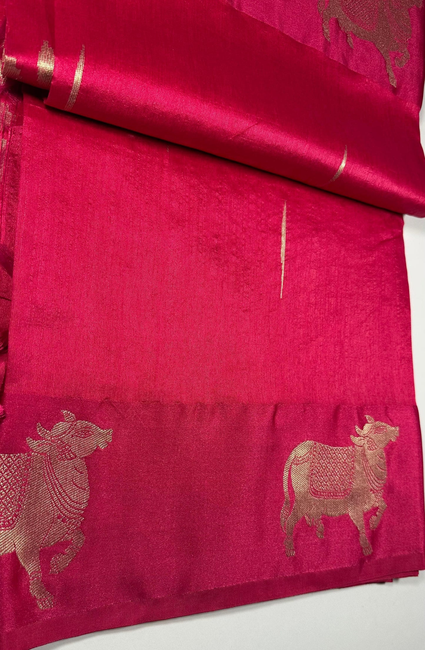 Magenta silk saree fabric texture with Gau Mata patterns and gold zari work showing spiritual and cultural significance