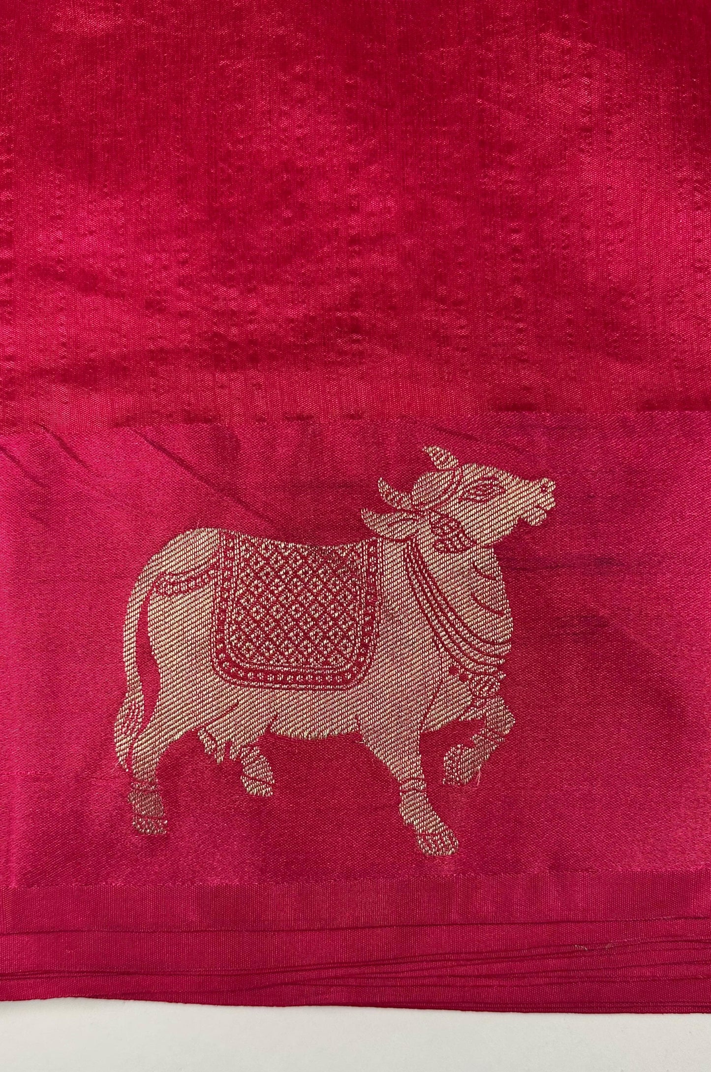 Traditional Hindu magenta silk saree with sacred cow motifs displayed showing religious and festival wear quality