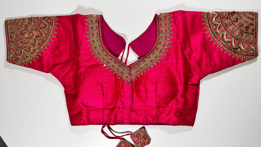 Bright pink embroidered saree blouse with heavy zardozi work showing traditional Indian bridal choli design with intricate gold handwork