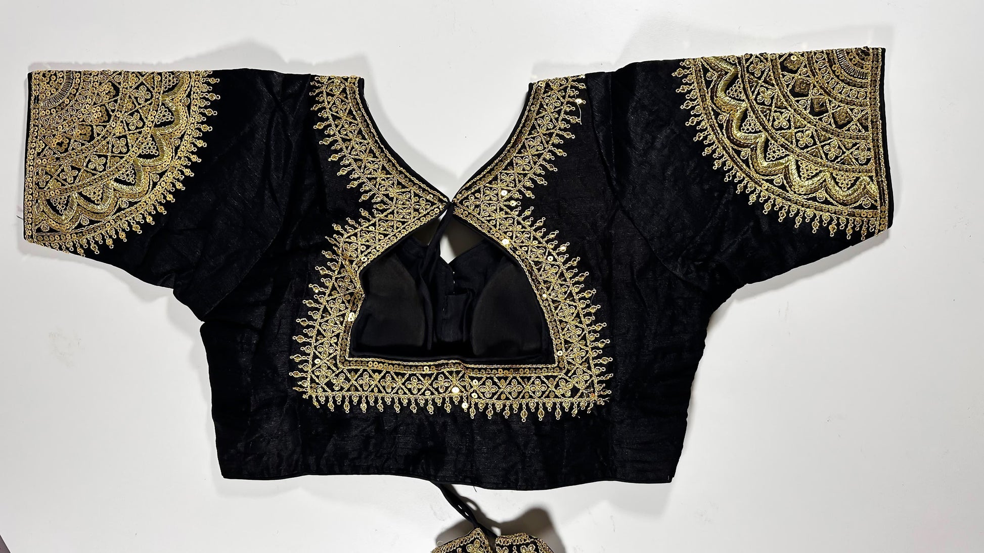 Back view of black silk blouse showing tie-up design with embroidered tassels and detailed traditional embroidery work