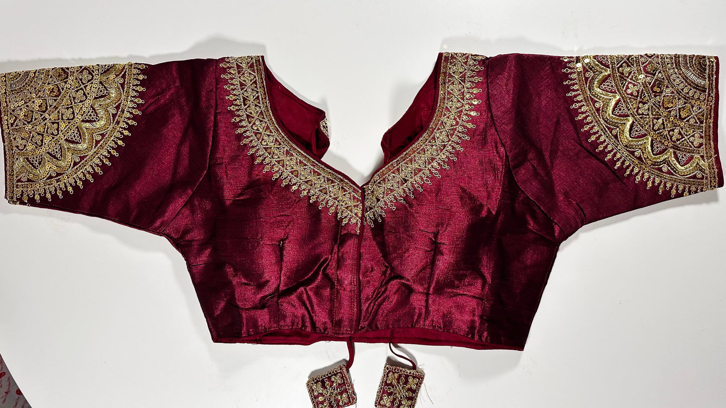 Wine maroon embroidered saree blouse with heavy zardozi work showing luxury Indian choli design with intricate gold handwork
