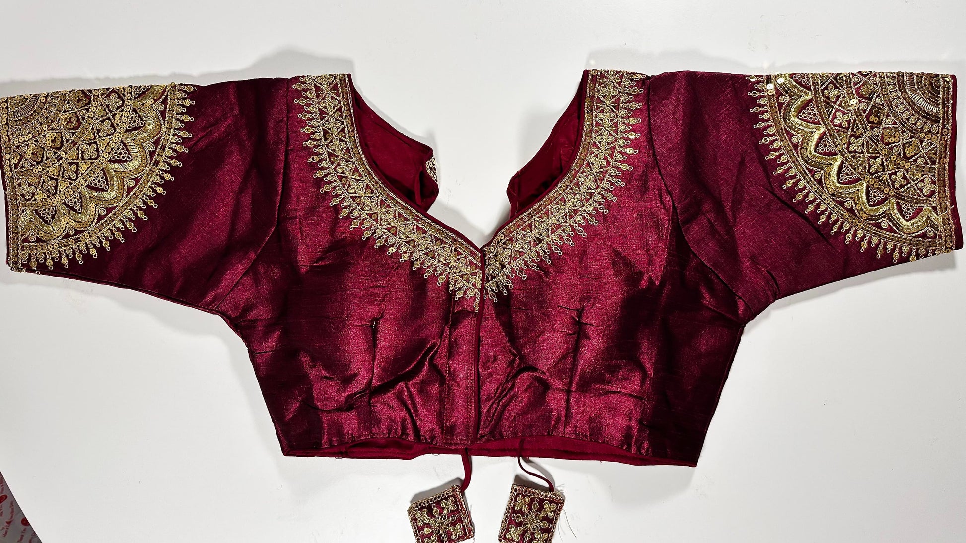 Wine maroon embroidered saree blouse with heavy zardozi work showing luxury Indian choli design with intricate gold handwork