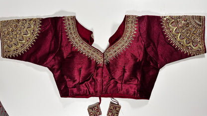 Wine maroon embroidered saree blouse with heavy zardozi work showing luxury Indian choli design with intricate gold handwork