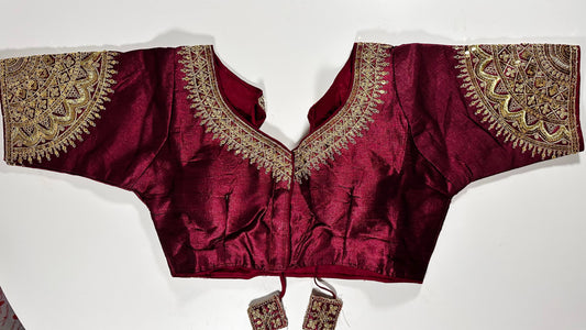 Wine maroon embroidered saree blouse with heavy zardozi work showing luxury Indian choli design with intricate gold handwork