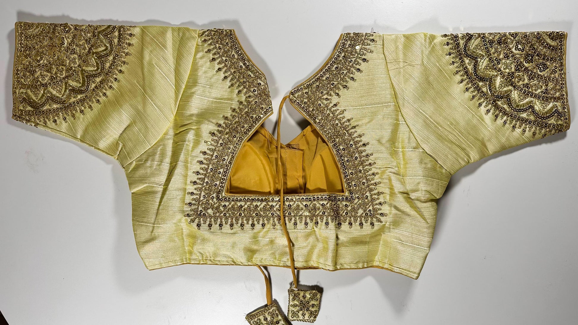 Golden embroidered saree blouse back view showing detailed threadwork, hook closure, and matching tassels - Indian wedding wear UK