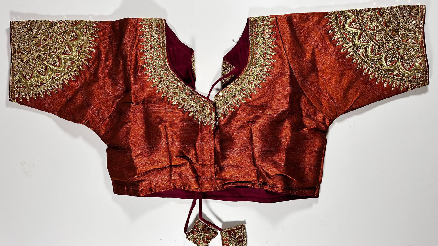 Rust red silk saree blouse with gold zardozi embroidery, featuring paisley motifs and traditional Indian threadwork - front view with decorative tassels