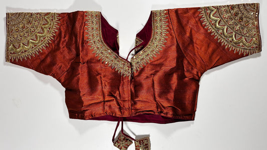 Rust red silk saree blouse with gold zardozi embroidery, featuring paisley motifs and traditional Indian threadwork - front view with decorative tassels