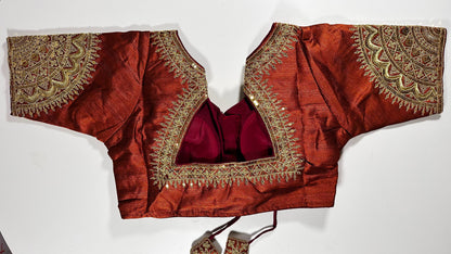 Back view of copper-red embroidered saree blouse showing detailed gold work, hook closure, and three-quarter sleeve design - Indian wedding wear UK