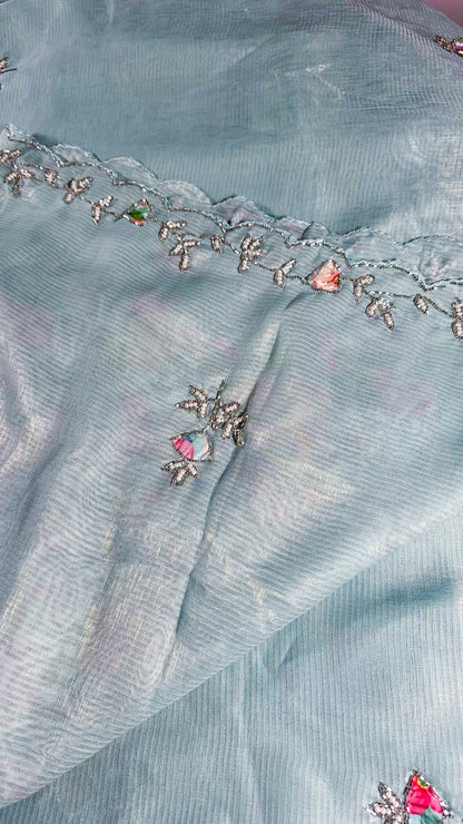 Close-up of embroidered floral motifs on powder blue saree with silver threadwork and coloured stone accents