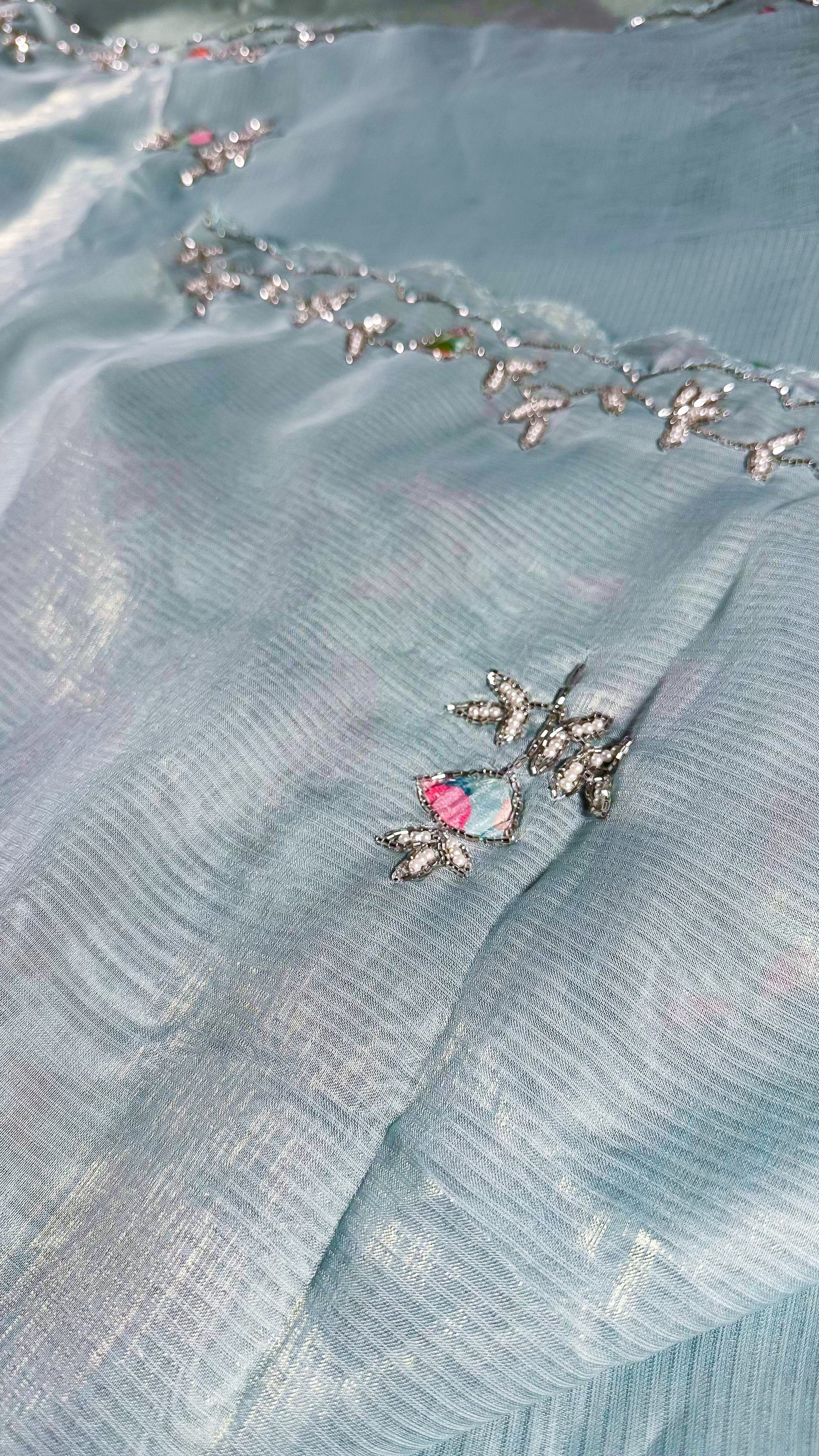 Detailed view of saree border embroidery with crystal embellishments and traditional vine patterns on silk fabric