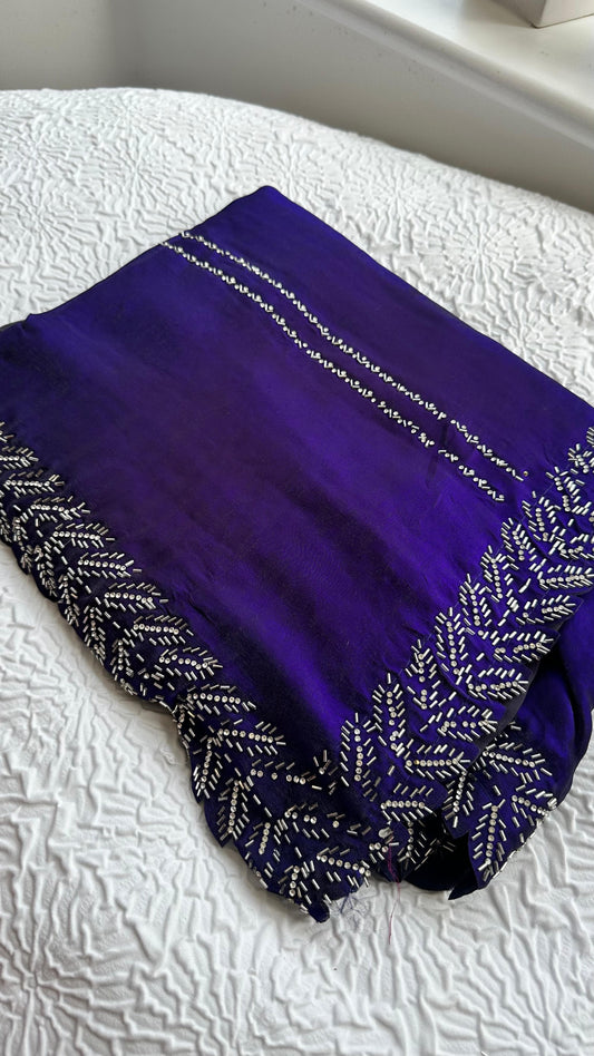 Elegant royal blue barberry saree with intricate silver gota work embroidery featuring detailed leaf patterns along the border, beautifully displayed on white textured background