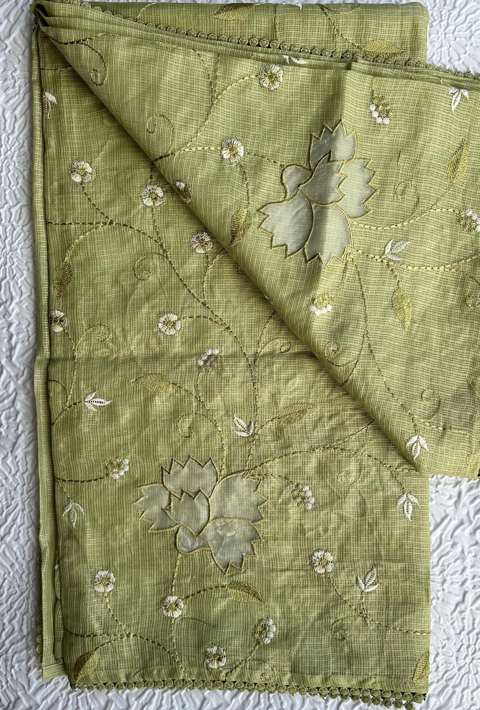 Beautiful olive green kota cotton saree with delicate lotus applique work and floral embroidery scattered across the fabric, featuring decorative scalloped border, displayed on white textured background