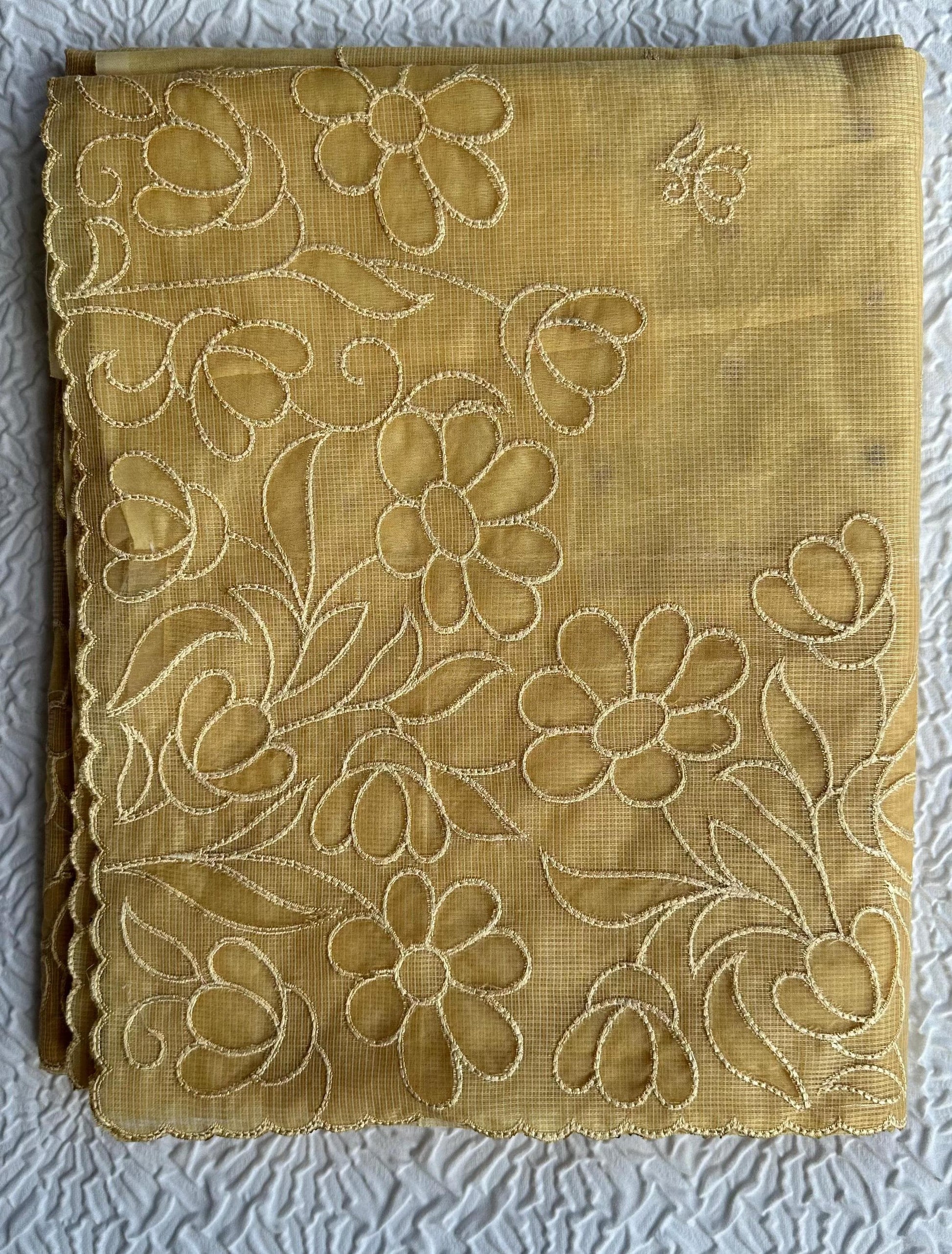 Radiant golden yellow kota cotton saree with beautiful floral applique work featuring delicate flower motifs and vine patterns with scalloped border detailing, elegantly displayed on white textured background