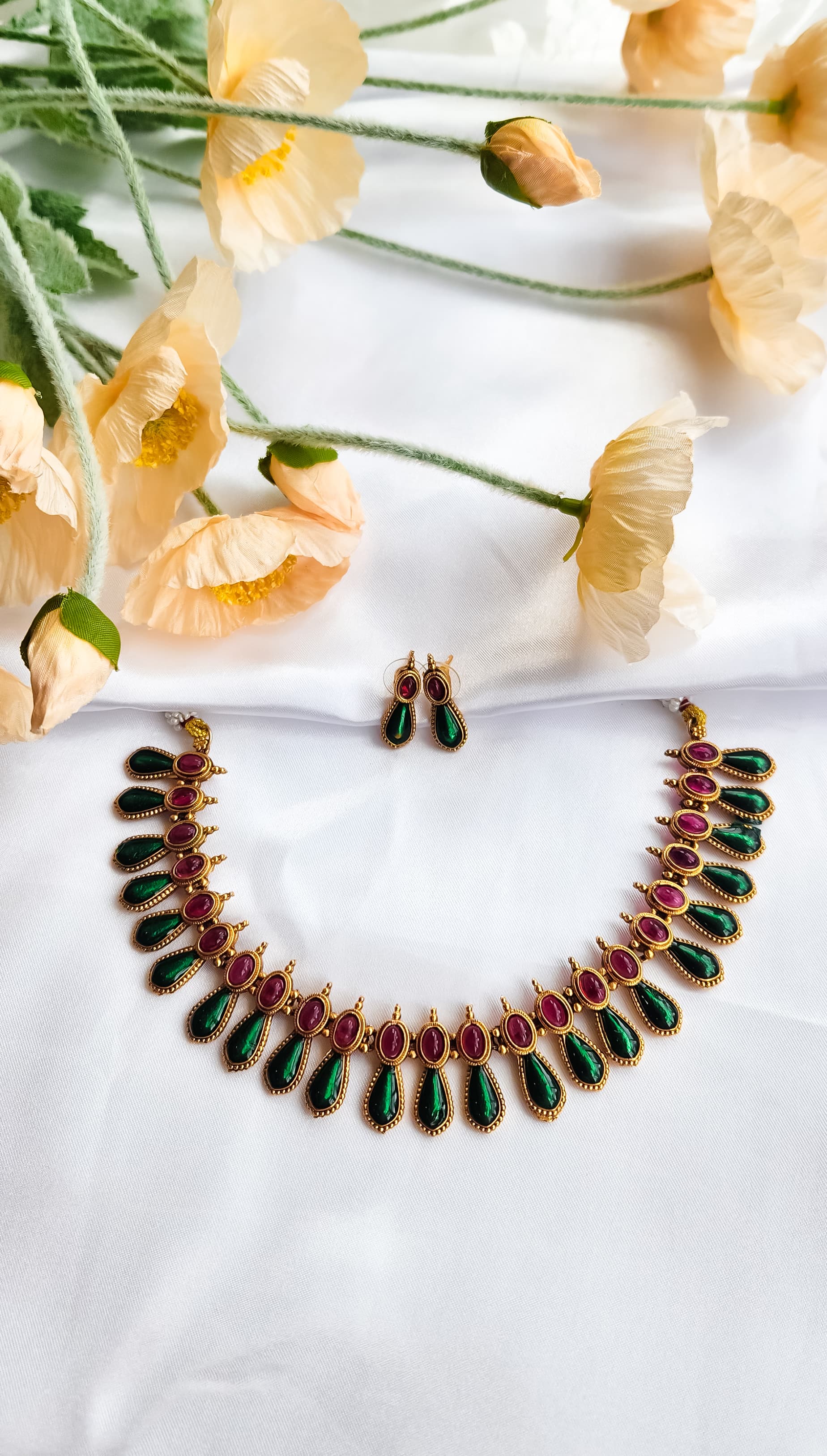 South Indian antique ruby-green heritage necklace set with matching earrings on white silk background