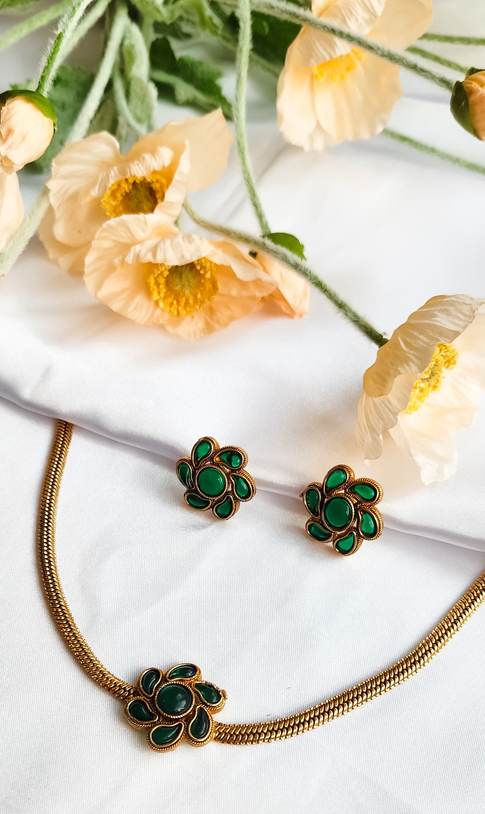 Green Floral Bloom Necklace Set with matching enamel flower earrings, displayed on white silk with floral backdrop.