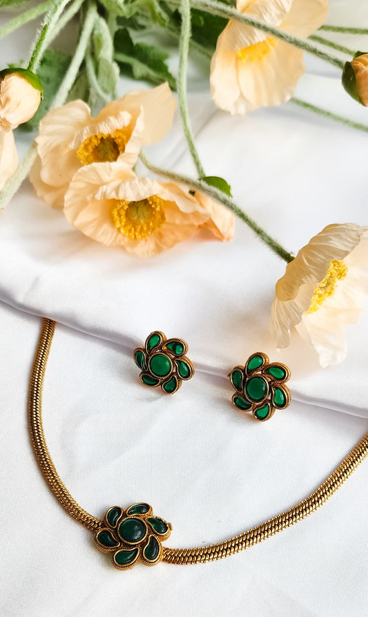 Green Floral Bloom Necklace Set with matching enamel flower earrings, displayed on white silk with floral backdrop.