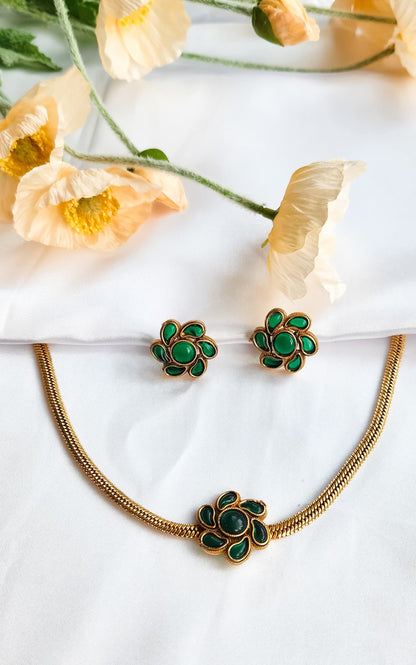 Green Floral Bloom Necklace Set with matching enamel flower earrings, displayed on white silk with floral backdrop.