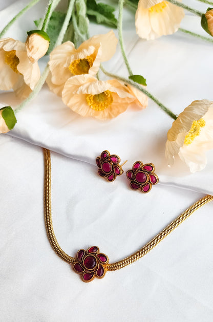 Pink Floral Bloom Necklace Set featuring enamel flower motif and earrings, styled elegantly against white fabric and flowers.