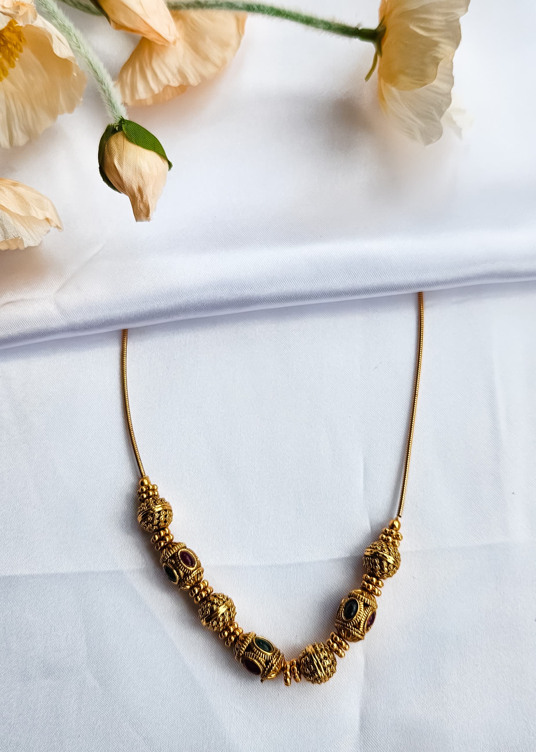 Antique beaded ball necklace with alternating red and green kemp stones on gold-plated wire, traditional South Indian temple jewelry design.