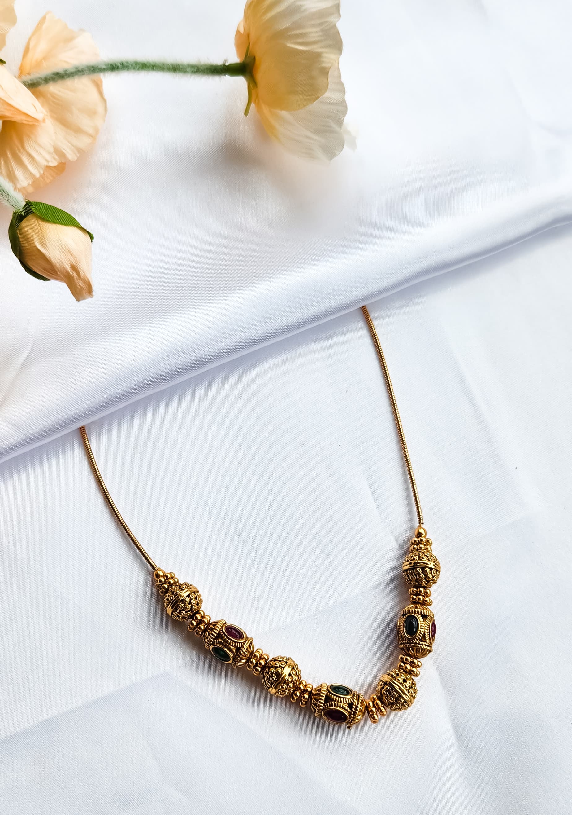 Antique beaded ball necklace with alternating red and green kemp stones on gold-plated wire, traditional South Indian temple jewelry design.