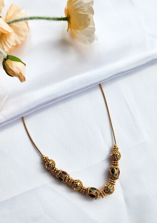 Antique beaded ball necklace with alternating red and green kemp stones on gold-plated wire, traditional South Indian temple jewelry design.