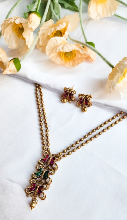 Gold finish butterfly design necklace with ruby and green stones, paired with matching butterfly earrings, golden bead chain.