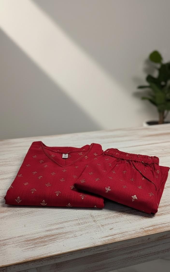 Folded red shirt with small patterns on a light wooden surface.