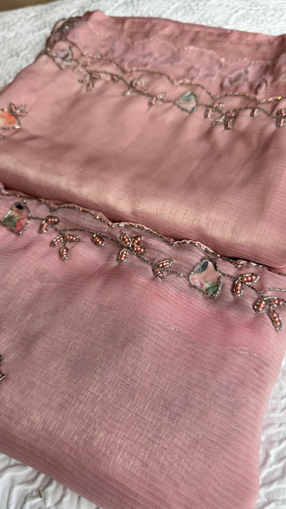 Close-up of pink saree fabric with floral bead embroidery and crystal-style accents.