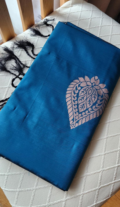Blue soft silk saree with silver zari paisley motifs and geometric patterned pallu displayed with tassels