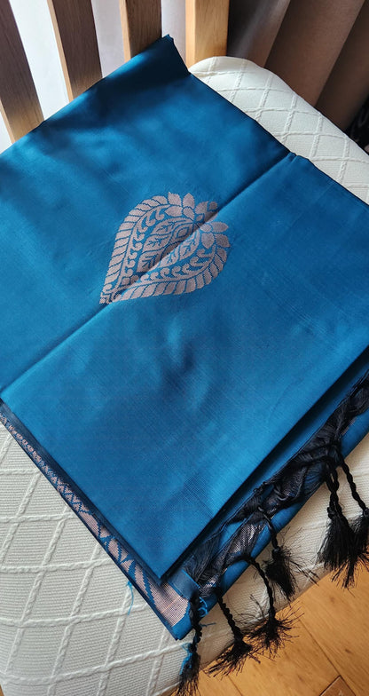 Blue soft silk saree with silver zari paisley motifs and geometric patterned pallu displayed with tassels