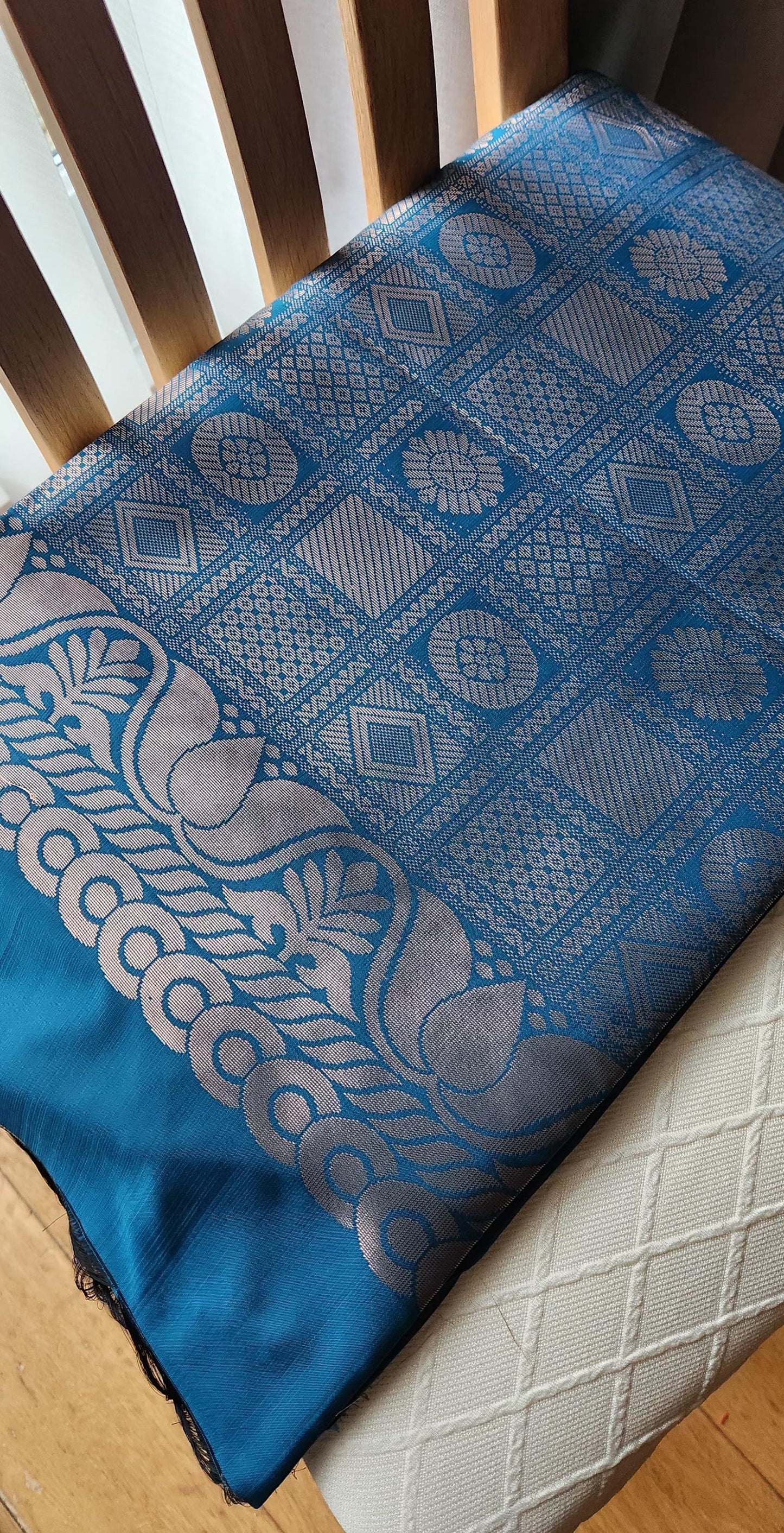 Blue soft silk saree with silver zari paisley motifs and geometric patterned pallu displayed with tassels