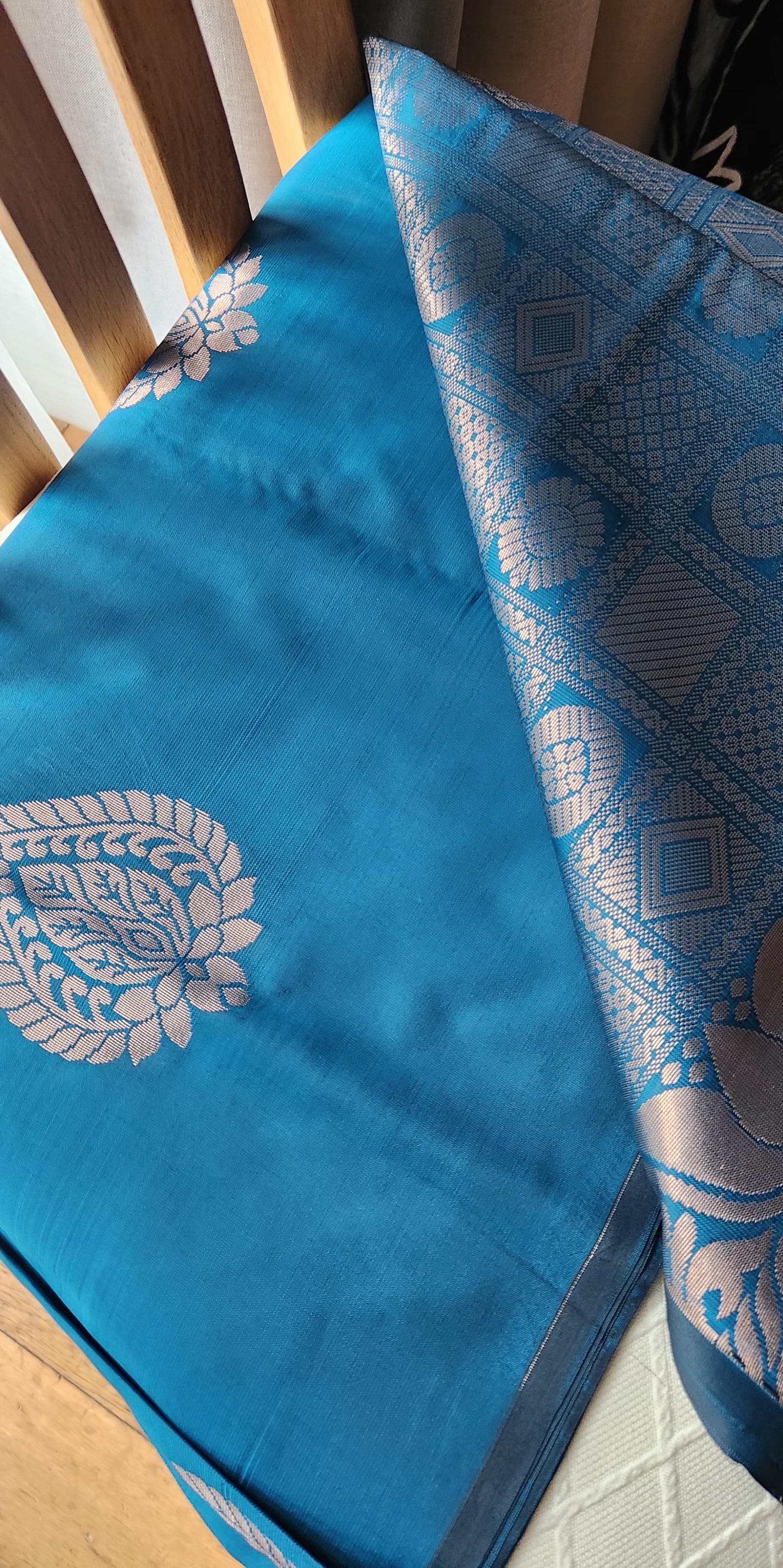 Blue soft silk saree with silver zari paisley motifs and geometric patterned pallu displayed with tassels